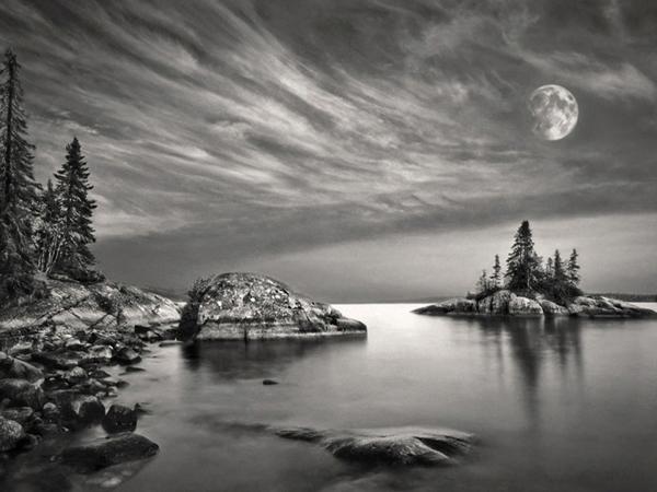 Black and white double exposure of moon and landscape along the Great Lakes Lake Superior in Ontario Canada
