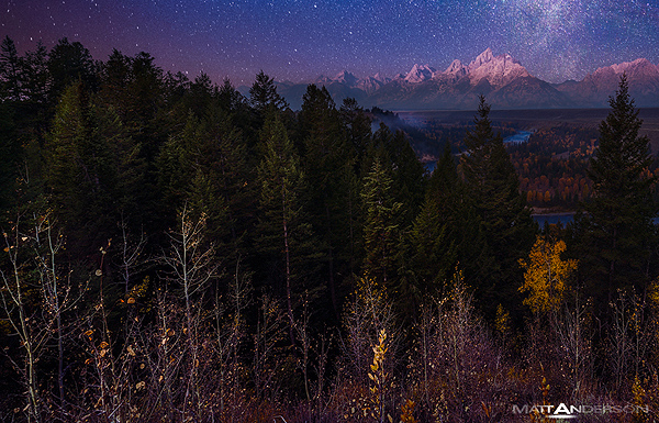 This is a multiple exposure of the Grand Tetons with a pre-dawn glow, light painting, and the Milky Way above. A long exposure for the sky and stars, a second exposure with light painting, and a third exposure of the first light bathing the Moutain tops. All taken hours apart. Below you can see the snake river twisting through the scene. Some distant smoke and fog layers the hillside and mountain bases.
