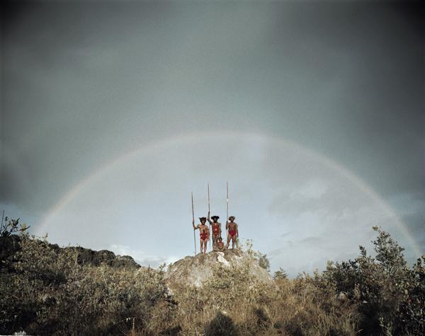 Old culture tribesmen posing in front of a rainbow in New Guinea. 