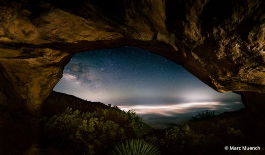 A photo looking through a cave to the starry sky beyond.